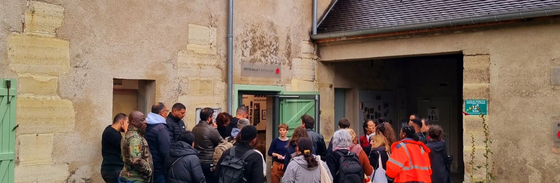 Groupe de visiteurs et visiteuses rentrant dans la petite salle d'exposition et de l'écomusée