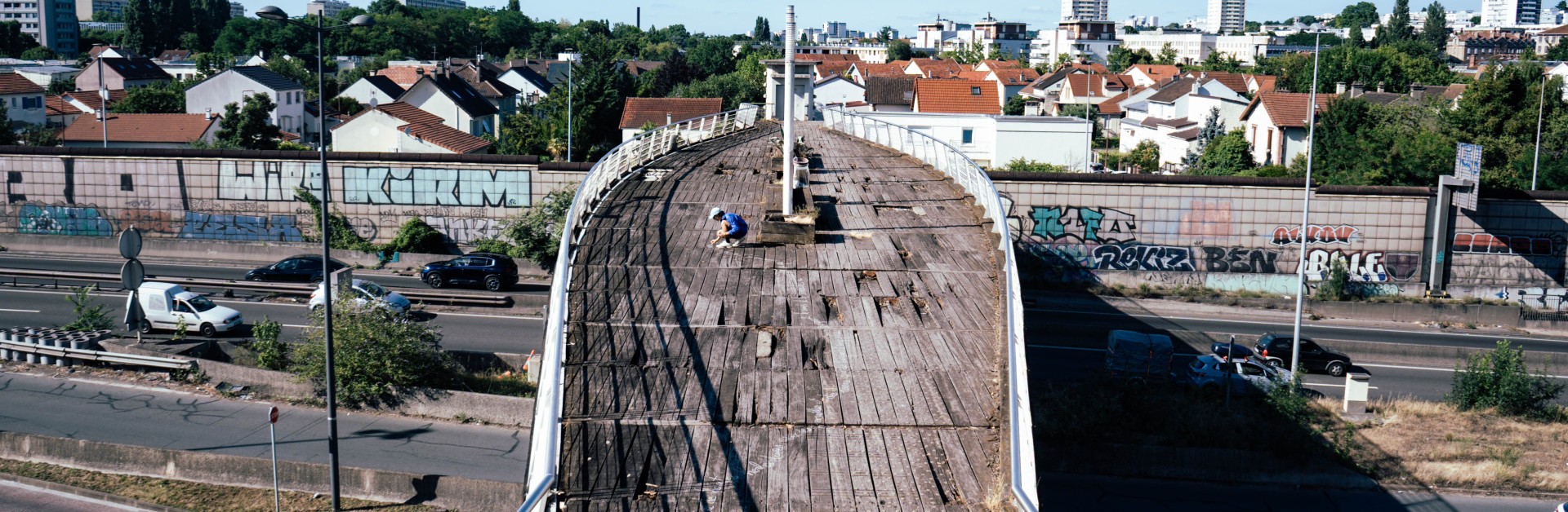 Photographie montrant l'artiste Malo Patron écrivant son texte sur la Bièvre sur la passerelle de Fresnes.