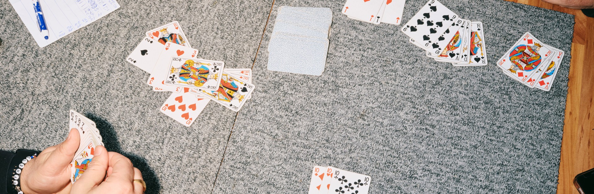 Table de café où quatre personnes jouent aux cartes