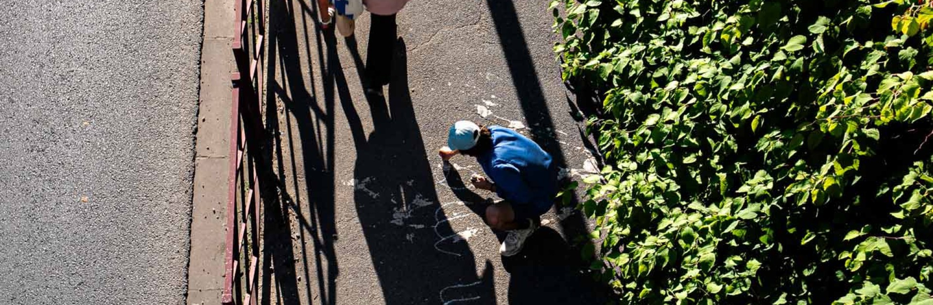 Vue aérienne de l'artiste Malo Patron écrivant sur un trottoir ses textes sur la Bièvre