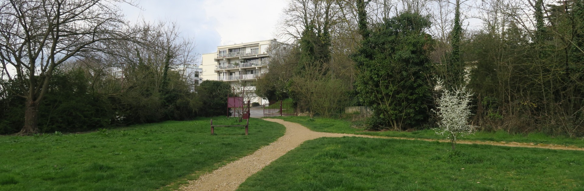 Photographie de l'entrée du parc des Aulnes, avec des pelouses, arbres et chemins