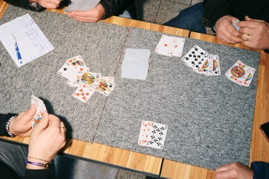 Table de café où quatre personnes jouent aux cartes