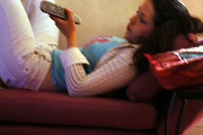 Jeune femme allongée sur un canapé, tenant une télécommande - Agrandir l'image 4 sur 12, fenêtre modale