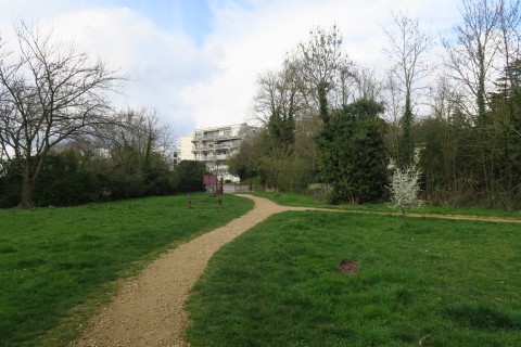 Photographie de l'entrée du parc des Aulnes, avec des pelouses, arbres et chemins